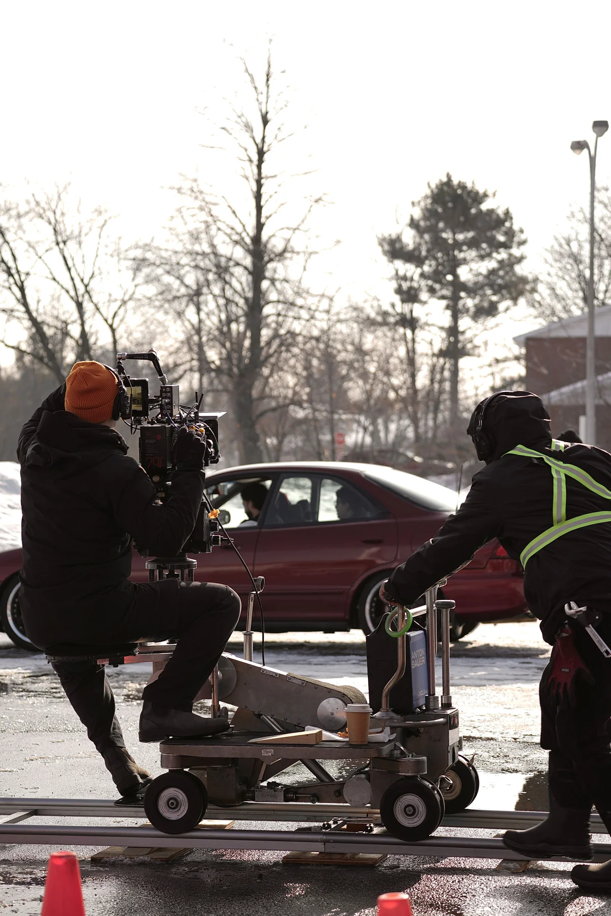 Camera crew working from a wheeled camera platform beside the picture vehicle.